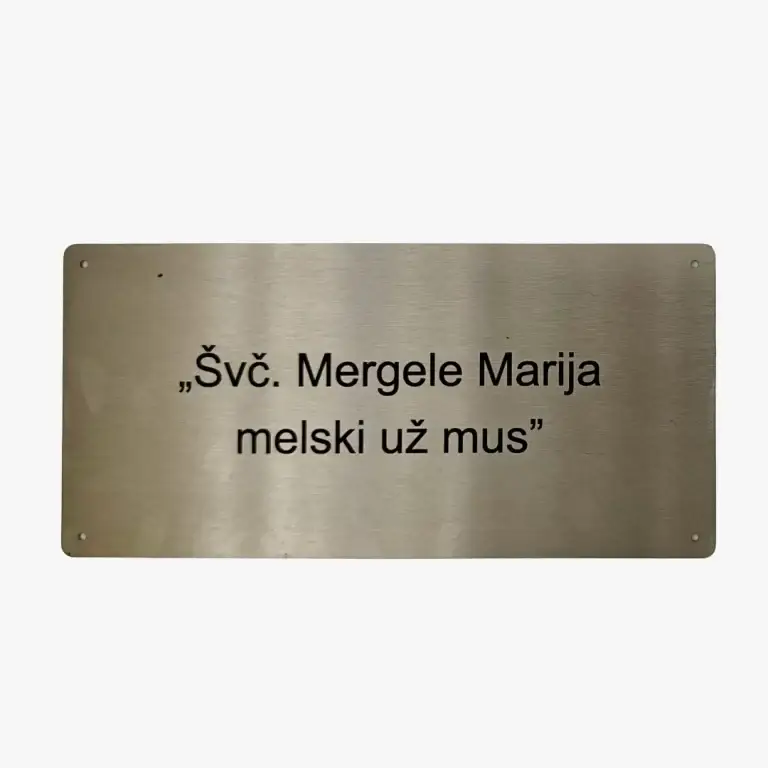 Nerūdijančio plieno plokštelė su graviruotu tekstu „Švč. Mergele Marija, melski už mus“ – ilgaamžis religinis simbolis.